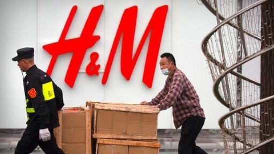 A security guard helps a worker move boxes past an H&amp;M clothing store at a shopping mall in Beijing, Friday, March 26, 2021. (AP)