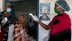 A woman checks the temperature of a voter before she casts her vote at a polling booth during the first phase of the West Bengal assembly election in Purulia district, (Reuters Photo)