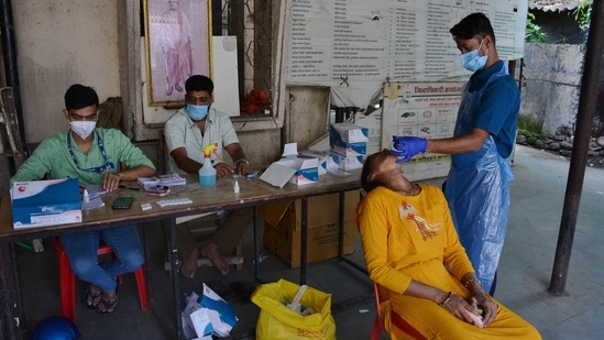 A health worker collects a swab sample to test for coronavirus infection, in Thane, India. (Photo by Praful Gangurde / Hindustan Times)