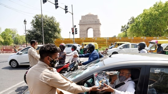 Civil Defence personnel distribute Covid-19 awareness kit to people ahead of the Holi festival, at India Gate in New Delhi. (ANI Photo)