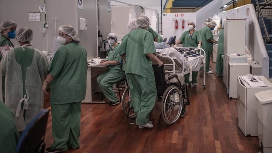 Healthcare workers treat Covid-19 patients inside a field hospital at the Pedro Dell'Antonia sports complex in Santo Andre, Brazil. (Bloomberg) Healthcare workers treat Covid-19 patients inside a field hospital at the Pedro Dell'Antonia sports complex in Santo Andre, Brazil. (Bloomberg)