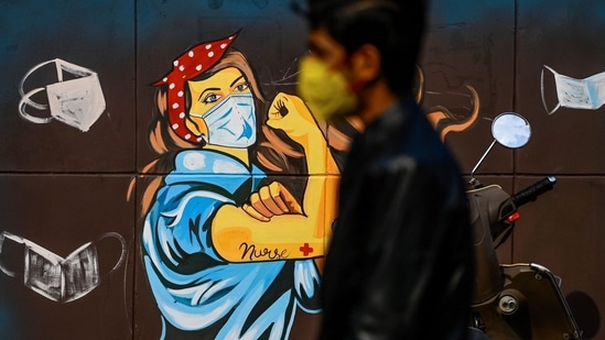 A man wearing a facemask as a preventive measure against the Covid-19 coronavirus walks past a mural in New Delhi, India.(Sajjad Hussain/AFP via Getty Images)