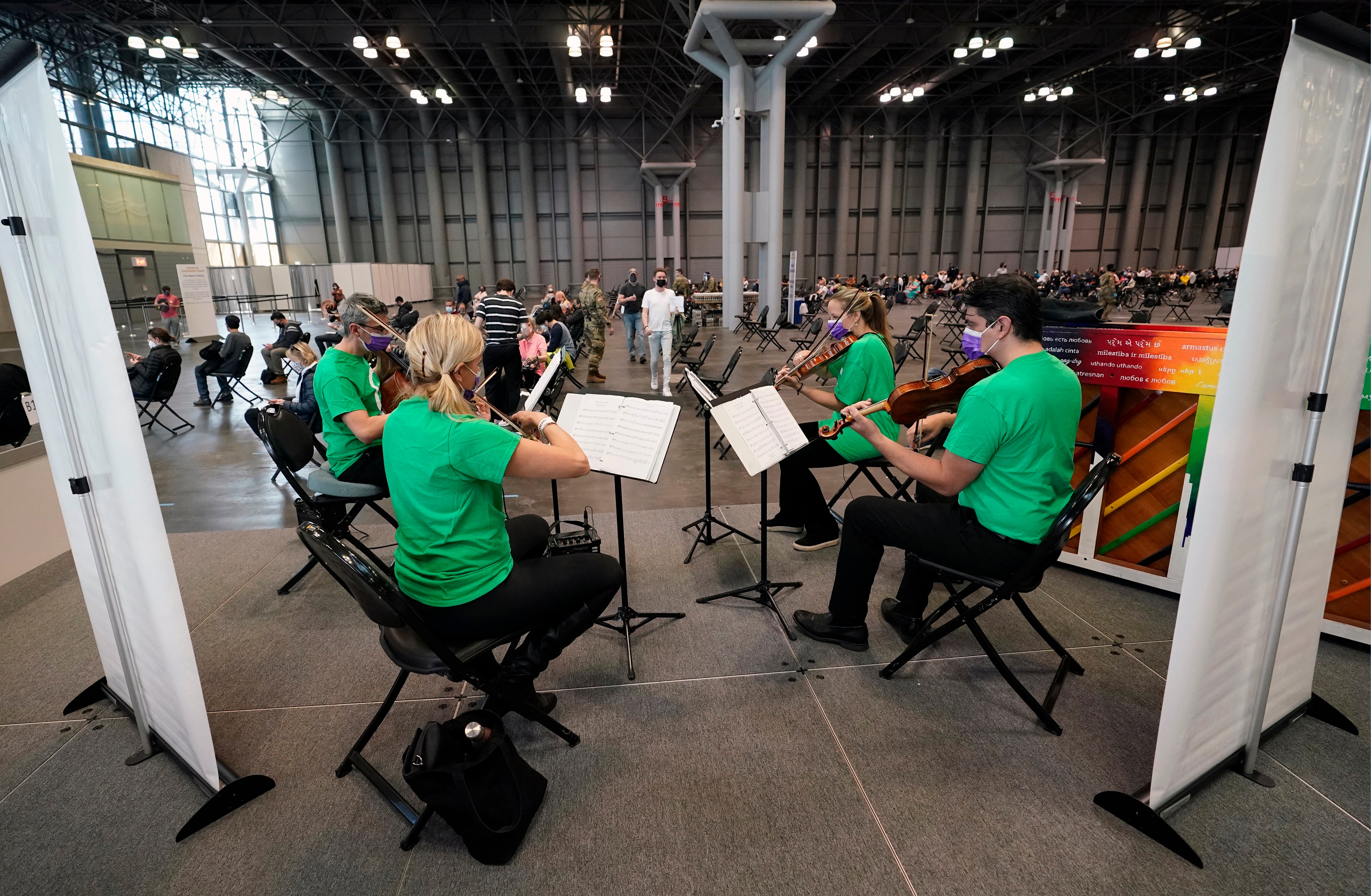 Victoria Paterson, second from right, plays with a string quartet while recently vaccinated people wait during a post-vaccination observation period inside the Jacob K. Javits Convention Center. (AP) Victoria Paterson, second from right, plays with a string quartet while recently vaccinated people wait during a post-vaccination observation period inside the Jacob K. Javits Convention Center. (AP)