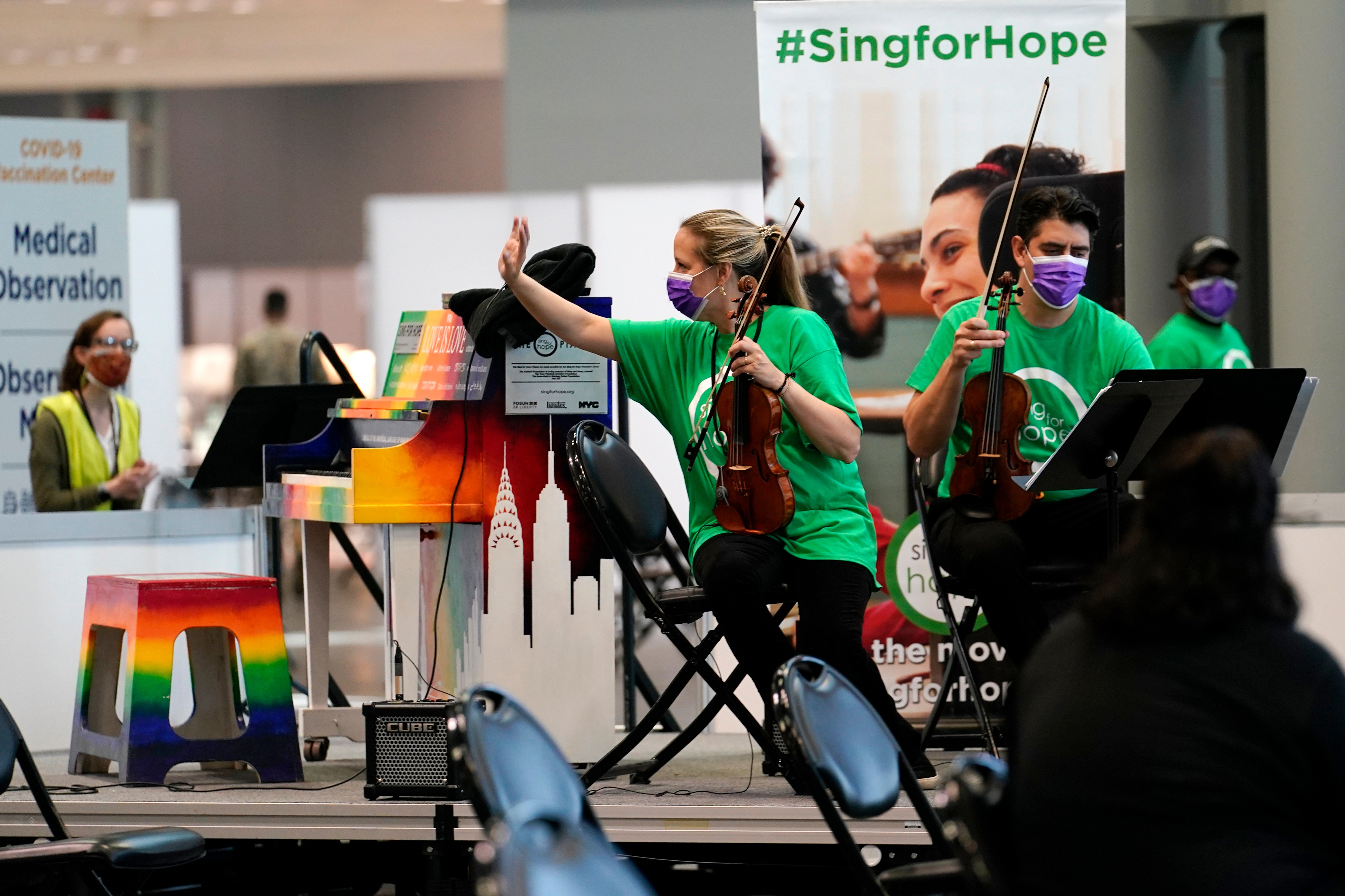 Violinist Victoria Paterson, center, waves as recently vaccinated people and health care workers applaud the music of a string quartet at the Jacob K. Javits Convention Center vaccination site. (AP) Violinist Victoria Paterson, center, waves as recently vaccinated people and health care workers applaud the music of a string quartet at the Jacob K. Javits Convention Center vaccination site. (AP)