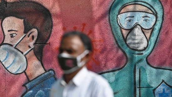 A pedestrian walks past a wall mural depicting frontline Covid-19 coronavirus warriors wearing face masks along a road.(AFP)