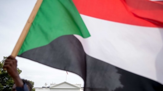 The White House is visible behind a man holding a Sudanese flag as Sudanese Americans rally outside the White House in Washington. (AP) The White House is visible behind a man holding a Sudanese flag as Sudanese Americans rally outside the White House in Washington. (AP)