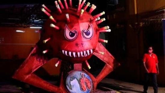 A man wearing a mask walks past an effigy of coronavirus in Mumbai on Sunday. (AP Photo) A man wearing a mask walks past an effigy of coronavirus in Mumbai on Sunday. (AP Photo)