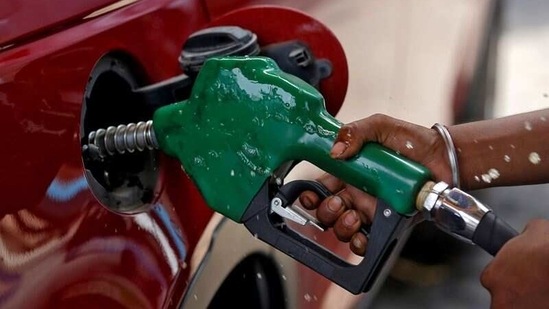 A worker holds a nozzle to pump petrol into a vehicle at a fuel station in Mumbai, India.(Reuters)