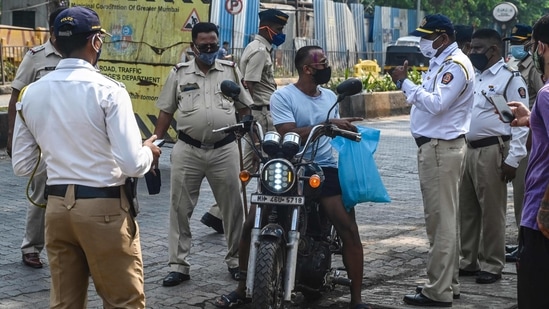 Police personnel stopping a motorist at a checkpoint during restrictions imposed around Holi as Covid-19 coronavirus cases rise, in Mumbai on March 29. The latest surge is centered in Maharashtra where authorities have tightened travel restrictions and imposed night curfews.(Indranil Mukherjee/AFP)