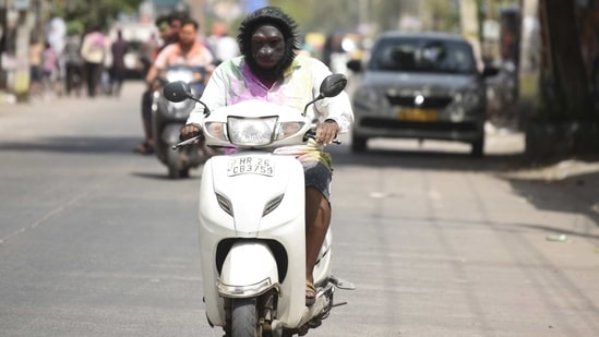 A motorist is seen wearing a costume mask to protect from splashes of colour during Holi, celebrations in Gurugram on March 29. (Parveen Kumar/HT Photo)
