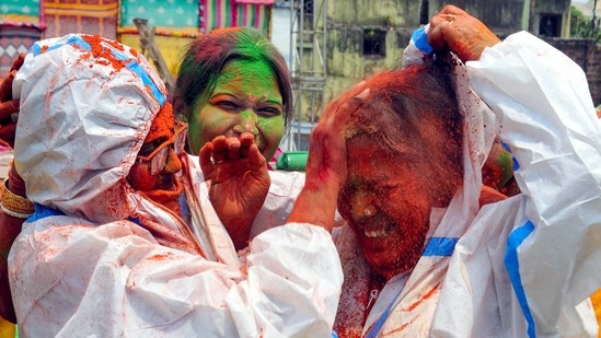 Kolkata: Women, wearing PPE kit, smear colours on each other during Holi festival, as coronavirus cases spike across the country, at Begumbazar in Kolkata, Monday, March 29, 2021. (PTI) Kolkata: Women, wearing PPE kit, smear colours on each other during Holi festival, as coronavirus cases spike across the country, at Begumbazar in Kolkata, Monday, March 29, 2021. (PTI)