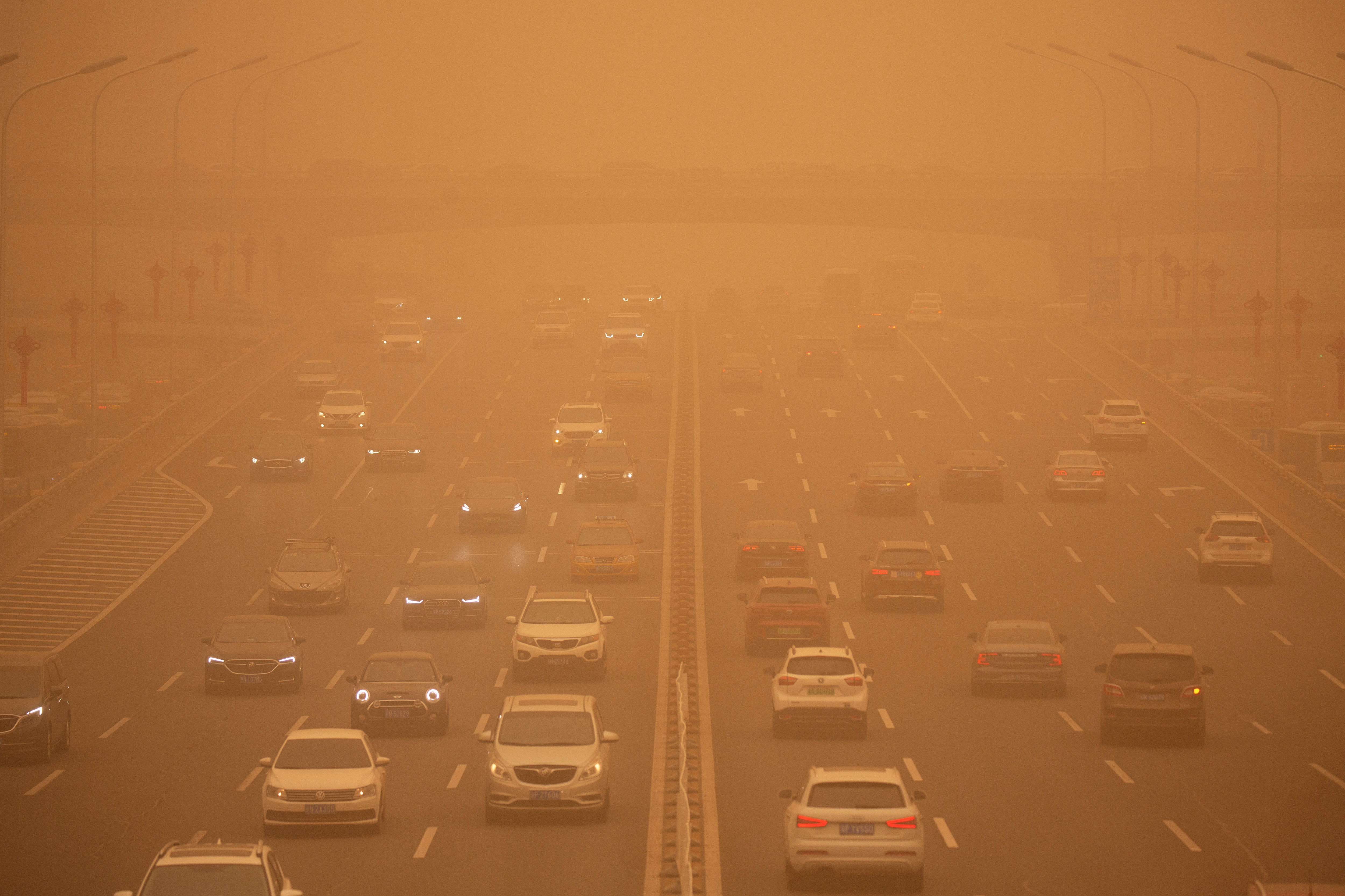 Cars are driven along an expressway amid a sandstorm during the morning rush hour in Beijing on March 15. (AP)