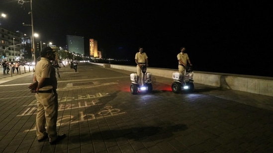 Police officers patrol on Segways along the promenade at Marine Drive during a night curfew in Mumbai on Monday. (Reuters Photo)