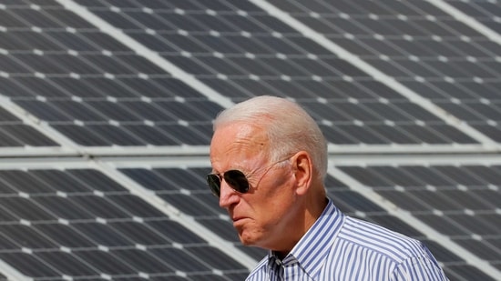 US President Joe Biden walks past solar panels.(REUTERS)