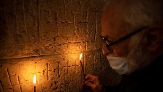Father Samuel Aghoyan, the Armenian superior at the Church of the Holy Sepulchre holds candles to illuminate crosses etched into the ancient stone wall of the Saint Helena chapel inside the church which is revered in Christian tradition as the site of Jesus' crucifixion and burial, during his interview with Reuters, in Jerusalem's Old City February 24, 2021.(REUTERS)