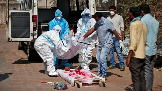 Relatives in PPE coveralls unload the body of a man, who died due to coronavirus disease from an ambulance for his cremation in Ahmedabad, on March 30. The disease also killed 354 people, which pushed the death toll to 1,62,468 on March 31. 41,280 patients were also discharged from hospitals, HT reported citing health ministry data.(Amit Dave / REUTERS)
