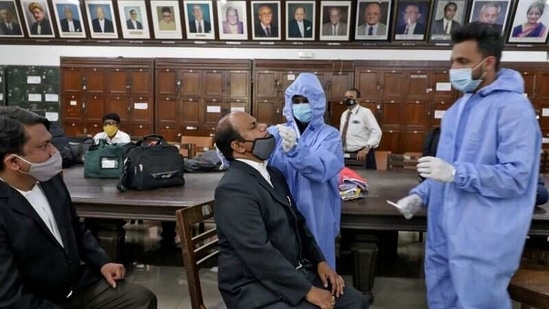 A health worker collects a swab sample from a court employee during a rapid antigen testing campaign, at a court in Mumbai, on March 25. Bhushan stressed that efficient implementation of "test, track and treat" remains the only proven strategy for control of transmission.(Niharika Kulkarni / REUTERS)