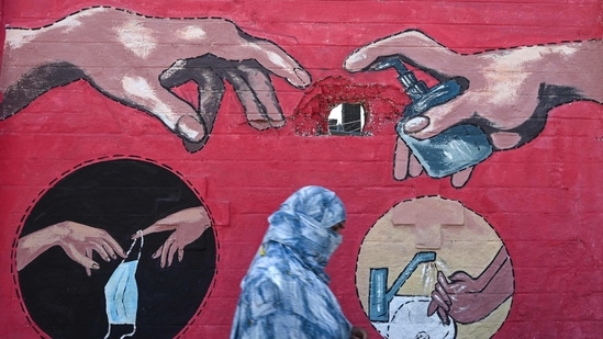 A pedestrian walks past a Covid-19 awareness mural-- a recreation of Michelangelo's "Creation of Adam," depicting a hand with a hand soap bottle, in Mumbai, on March 31. The active cases have been increasing for more than 20 days and now comprise 4.47 per cent of the total infections, while the recovery rate has further dropped to 94.19 per cent, HT reported citing health ministry data.(Indranil Mukherjee / AFP)