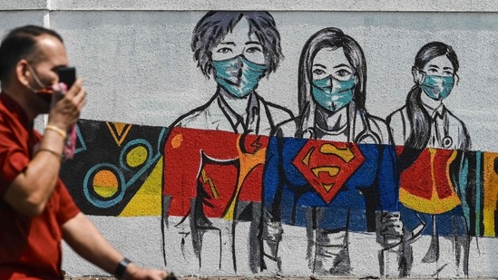 A man cycles past a wall mural depicting health workers as superheroes amidst rising Covid-19 coronavirus cases, in Mumbai. (AFP) A man cycles past a wall mural depicting health workers as superheroes amidst rising Covid-19 coronavirus cases, in Mumbai. (AFP)