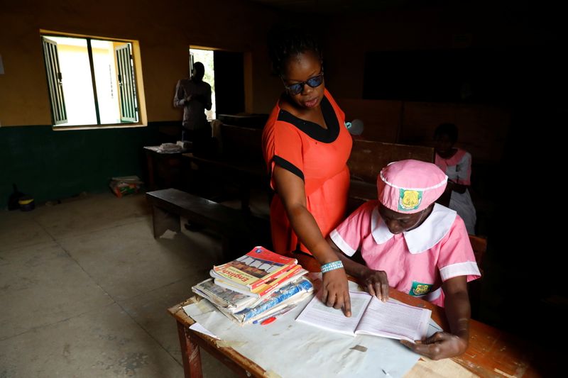 Shade Ajayi, 50, is helped by a teacher at Ilorin Grammar School in Ilorin, Kwara state. (REUTERS)