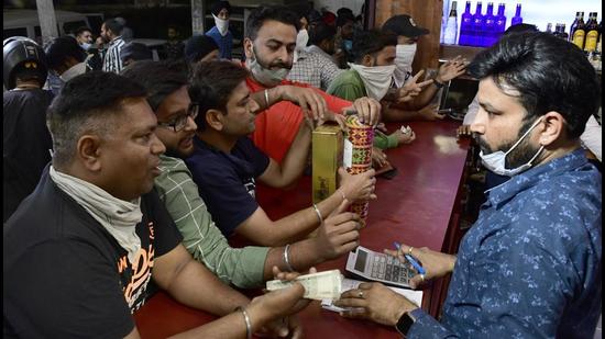 Bacchus lovers flouting social distancing norms as they try to secure a stock of their preferred brand of liquor. (Harsimar Pal Singh/HT)