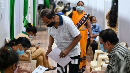 A volunteer assists people to fill personal information forms before getting inoculated, at a vaccination centre, in Mumbai, on April 1. As on Day-75 of the vaccination drive (31st March), 20,63,543 vaccine doses were given. Out of which, 17,94,166 beneficiaries were vaccinated across 39,484 sessions for 1st dose and 2,69,377 beneficiaries received 2nd dose of vaccine, PTI reported.(Punit Paranjpe / AFP)