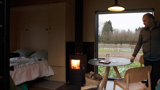 Guy De Deyn, menikmati perapian kayu saat dia menyiapkan meja untuk permainan kartu di Slow Cabin di Elewijt, Belgia, Senin, 15 Februari 2021. Kabin Lambat ini, yang dibangun di pedesaan Belgia, adalah cara baru untuk liburan di masa pandemi: dalam kesunyian total dan di antah berantah. Kabin kayu sepenuhnya berkelanjutan, asalkan Anda tidak mandi terlalu lama dan Anda bisa hidup tanpa Wi-Fi. (Foto AP / Virginia Mayo) (AP)