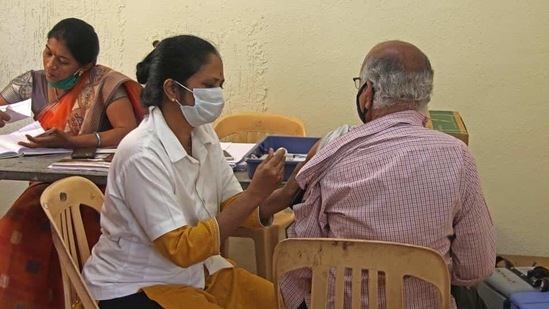 Health worker giving Covid vaccine to a senior citizen at vaccination centre.