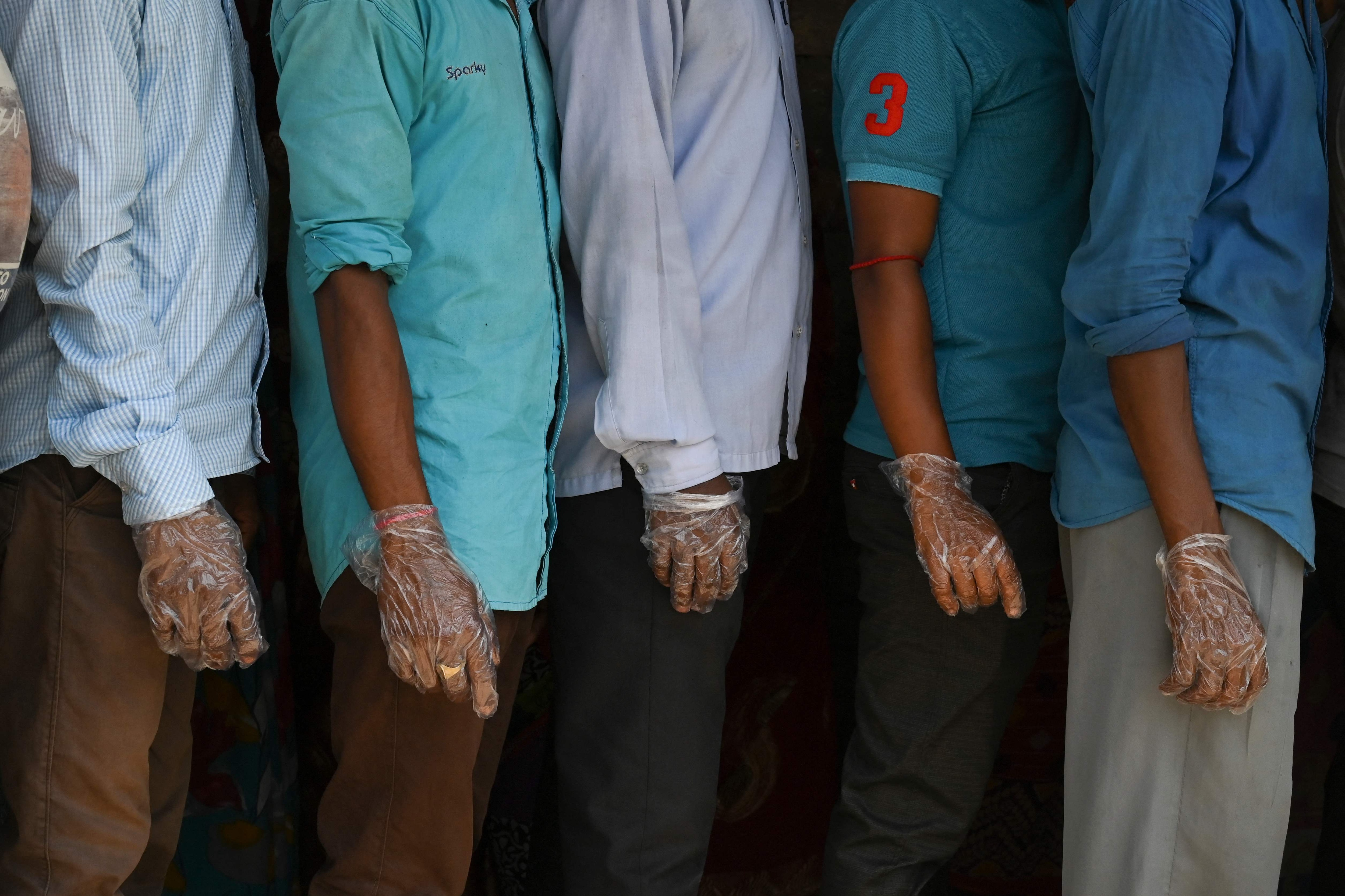 Voters wearing plastic gloves stand in a line to cast their vote outside a polling station during Phase 2 of West Bengal's legislative election in Nandigram on April 1, 2021. (Photo: AFP) Voters wearing plastic gloves stand in a line to cast their vote outside a polling station during Phase 2 of West Bengal's legislative election in Nandigram on April 1, 2021. (Photo: AFP)