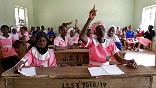 Shade Ajayi raises her hand to answer a question during class at Ilorin Grammar School in Ilorin, on March 25. Sitting at a wooden desk while donning the pink dress and bonnet that make up her uniform, Ajayi joins hundreds of similarly dressed pupils aged 11 to 13 at a school in Ilorin, in Nigeria's western Kwara state.(Temilade Adelaja / REUTERS)