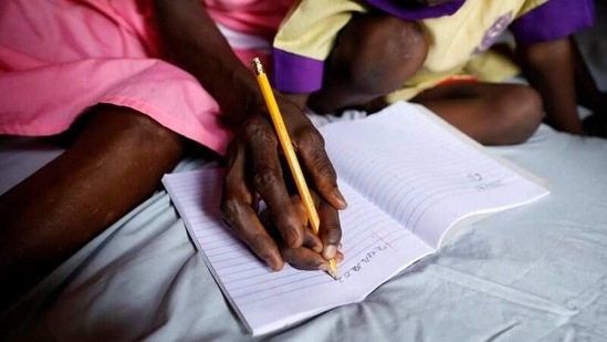 Ajayi helps her six-year-old granddaughter Deborah Adeboye with her homework, at her home in Ilorin on March 24. It has been hard to juggle school and work, and deal with the stigma. Her daughter, Shola Adeboye, said she was initially embarrassed that her mother attended school alongside children, but later came around.(Temilade Adelaja / REUTERS)