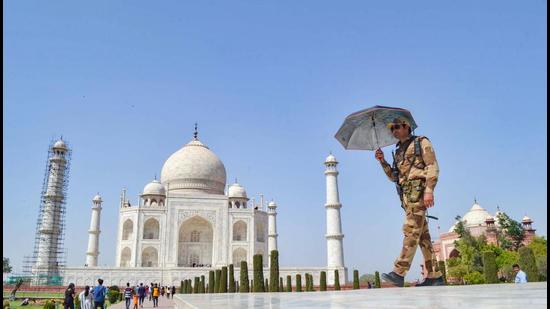 A CISF personnel walks under an umbrella while guarding at Taj Mahal on a hot day, in Agra, Wednesday, March 31. (PTI) A CISF personnel walks under an umbrella while guarding at Taj Mahal on a hot day, in Agra, Wednesday, March 31. (PTI)