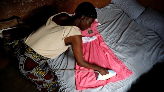 Ajayi irons her school uniform as she prepares for school, at her home in Ilorin on March 25. She intends to continue her education for four more years, saying it will help her business. "I'm not ashamed that I wear a uniform," Ajayi said.(Temilade Adelaja / REUTERS)