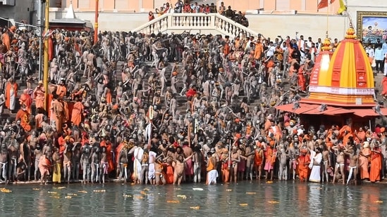 Naga Sadhus (Hindu holy men) gather before taking a holy dip in the waters of the River Ganga. Even as authorities upped their guards in view of the Covid-19 pandemic and mandated devotees to carry a negative RT-PCR certificate, many turned up without it on day-1 of the fest, according to news agency PTI.(AFP)
