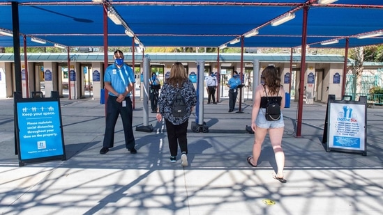 Visitors walk past signs indicating health and safety guidelines in Valencia, California.(AFP)