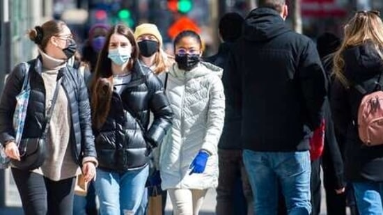 People wear face masks as they walk along a street in Montreal. (AP Photo)
