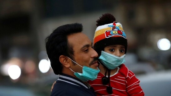 A man and child with protective masks walk outside a market as the coronavirus disease (Covid-19) pandemic continues, in Karachi, Pakistan.