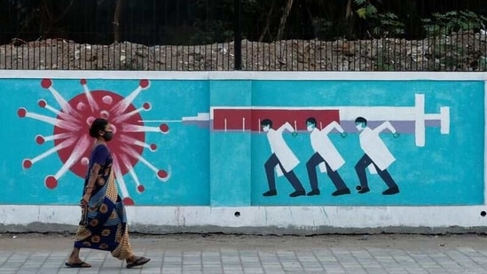 A woman wearing a protective face mask walks past a graffiti, amidst the spread of the coronavirus disease (Covid-19), on a street in Mumbai, India, March 30, 2021. (REUTERS)