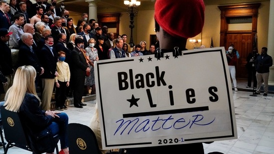 A person wears a "Black Lies Matter" sign as Georgia Governor Brian Kemp speaks during a news conference on Saturday about Major League Baseball's decision to pull the 2021 All-Star Game from Atlanta over a new voting law. (AP Photo/Brynn Anderson) A person wears a "Black Lies Matter" sign as Georgia Governor Brian Kemp speaks during a news conference on Saturday about Major League Baseball's decision to pull the 2021 All-Star Game from Atlanta over a new voting law. (AP Photo/Brynn Anderson)