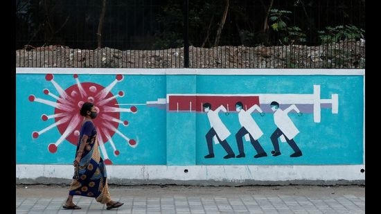 A woman wearing a protective face mask walks past a graffiti, amid the spread of the coronavirus disease, Mumbai, March 30, 2021. (REUTERS) A woman wearing a protective face mask walks past a graffiti, amid the spread of the coronavirus disease, Mumbai, March 30, 2021. (REUTERS)