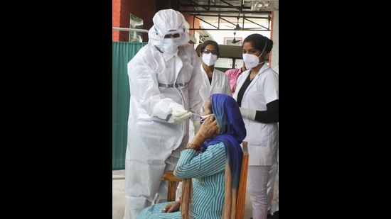 A medic takes a sample from a woman for COVID-19 test at a government dispensary in Patiala. (PTI)