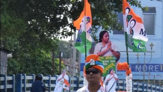 A TMC supporter rides a scooty with a cut-out of West Bengal chief minister Mamata Banerjee and party flags in Kolkata. (ANI)