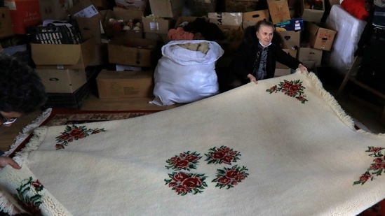 Hate Ora or 'Aunt Hate', 64, as everyone knows her, holds a carpet in Kukes town, northeastern Albania, Friday, March 12, 2021. (AP)