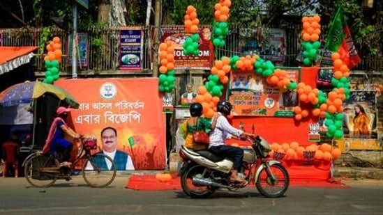 Commuters on two wheelers ride past a decorated platform of Bharatiya Janata Party ahead of the third phase of West Bengal state elections in Kolkata, India, Monday, April 5, 2021. (AP) Commuters on two wheelers ride past a decorated platform of Bharatiya Janata Party ahead of the third phase of West Bengal state elections in Kolkata, India, Monday, April 5, 2021. (AP)