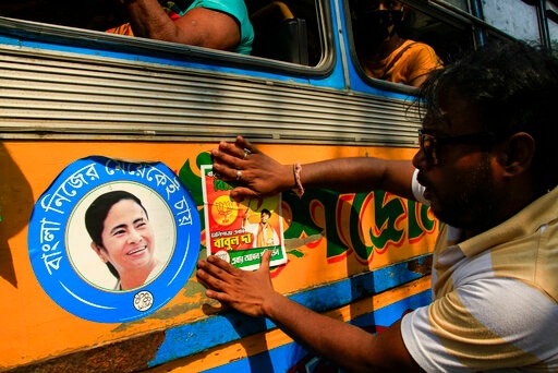 A BJP supporter fixes a party poster in support of party candidate on the body of a bus beside an image of West Bengal chief minister Mamata Banerjee, in Kolkata on Monday.(AP Photo) A BJP supporter fixes a party poster in support of party candidate on the body of a bus beside an image of West Bengal chief minister Mamata Banerjee, in Kolkata on Monday.(AP Photo)