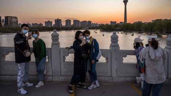 People taking photos at a local park at sunset during the Qinming festival holiday on April 4 in Beijing. China reported 32 new Covid-19 cases on April 4, up from 21 a day earlier, marking the highest daily total in more than two months, the national health authority said on April 5.(Kevin Frayer/Getty Images)