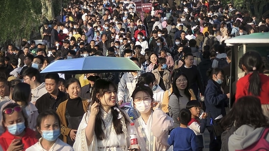 Visitors, some wearing face masks to protect against Covid-19, walk across a causeway at the West Lake in Hangzhou in eastern China's Zhejiang Province on April 4. Domestic tourists were out in force at some of China's most popular tourist sites over the holiday weekend as the country continued to report new cases of the coronavirus within its borders.(Mark Schiefelbein/AP)