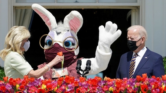 U.S. President Joe Biden stands to deliver his remarks on the tradition of Easter, next to first lady Jill Biden holding a flower and a person wearing an Easter Bunny costume at the Blue Room Balcony of the White House in Washington, U.S. April 5, 2021. (REUTERS)