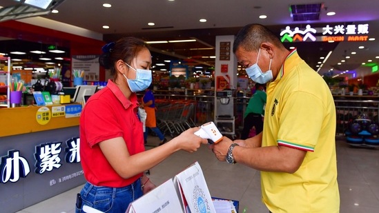 A resident goes through health screening to enter a supermarket in Ruili, southwestern China's Yunnan Province on April 1. The city accounted for all of the 15 new local cases reported on April 4. The total number of new Covid-19 infections, including imported infections originating from overseas, stood at 32, marking the highest total since January 31.(Chen Xinbo/Xinhua via AP)