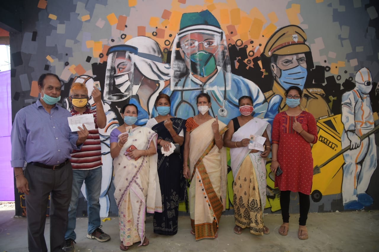 Voters pose before a striking wall art dedicated to Covid-19 warriors after casting their vote.  (CEO Assam)